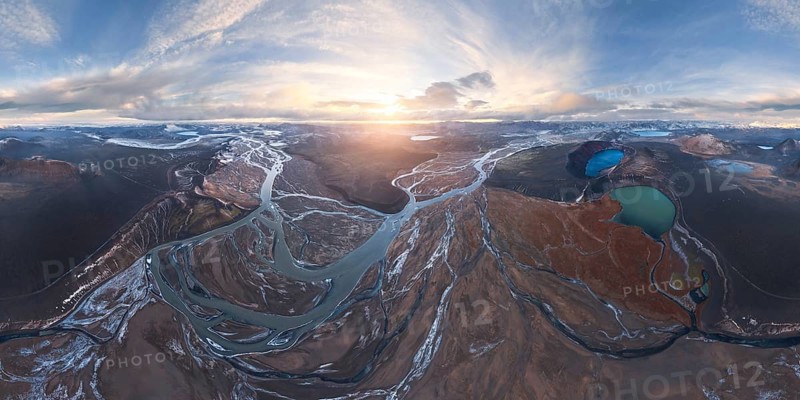 A breathtaking aerial view of Iceland's Highlands at sunrise, showcasing meandering rivers, volcanic landscapes, and glacial vistas under a vast, dramatic sky