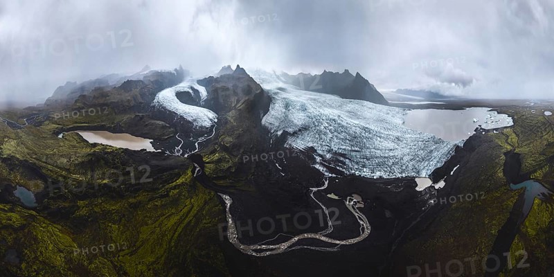 A breathtaking panoramic view of Vatnajokull glaciers in Iceland's Highlands Features vast ice expanses, rugged mountains, and serene lakes under a moody sky