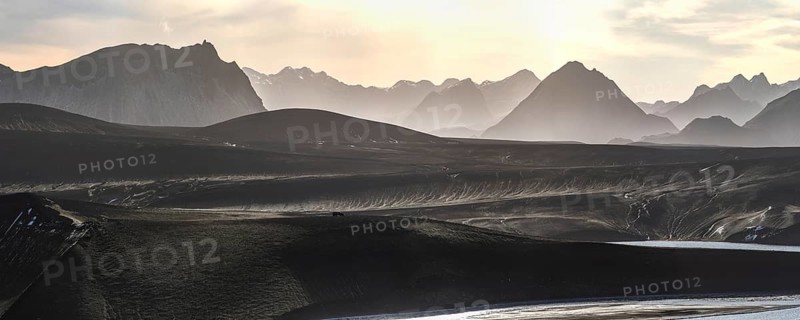 Captivating panoramic view of the Icelandic Highlands at sunset Mist gently blankets the mountains, creating a serene and ethereal atmosphere under a soft, glowing sky