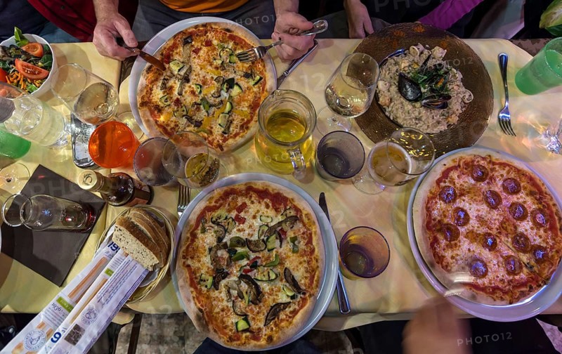 Different pizzas and mussel dishes on a table in a restaurant, Italy