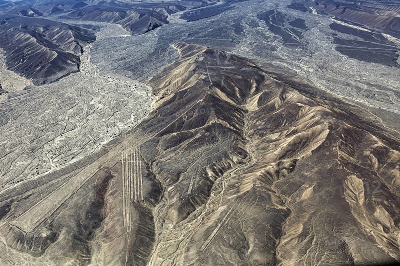 Aerial view shows mountainous desert landscape with clear geoglyph lines, the geoglyphs and images in the desert near Nasca and Palpa in Peru