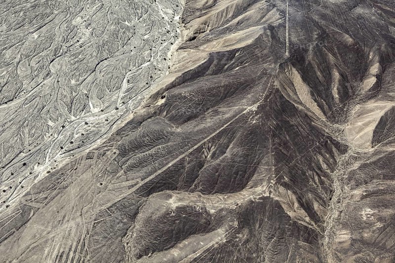 Aerial photo shows hills with extensive line patterns in an arid region, the geoglyphs and images in the desert near Nasca and Palpa in Peru