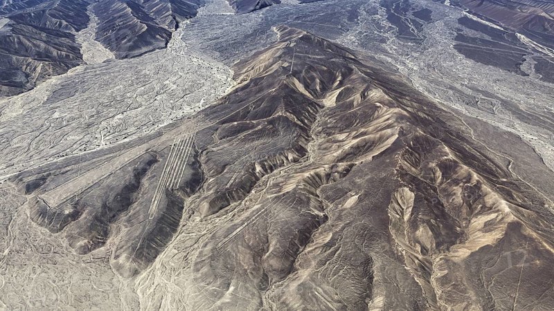 Mountain ranges in a dry desert landscape with clear geoglyph patterns, the geoglyphs and images in the desert near Nasca and Palpa in Peru