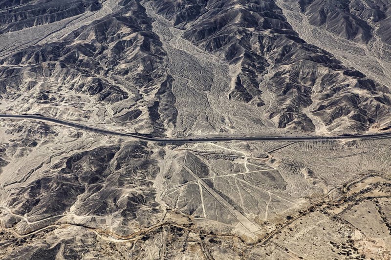 Barren landscape with visible geoglyphs and a straight road, the geoglyphs and images in the desert near Nasca and Palpa in Peru