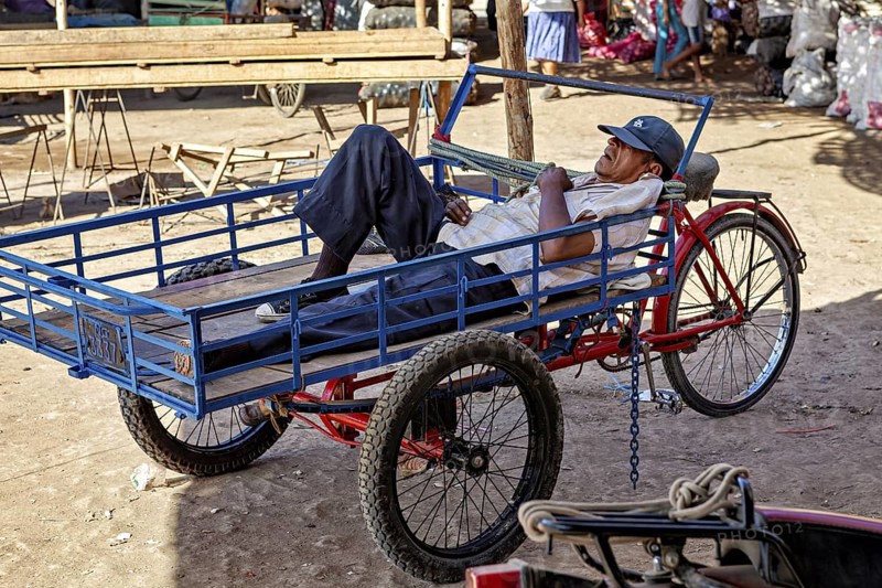 A man resting on a cart in a sunny market environment, The market in the streets of Nasca in Peru