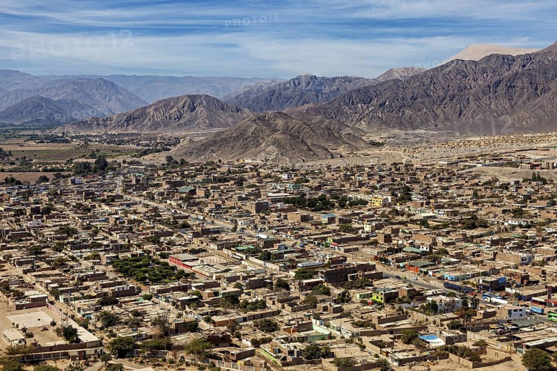 A panoramic view of a city against a backdrop of mountains and clear skies, the city of Nasca in Peru
