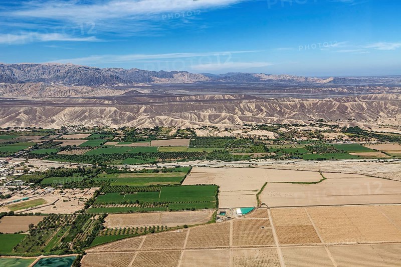 View of a mix of fields and dry landscapes with mountain range, The desert landscape near Nasca in Peru