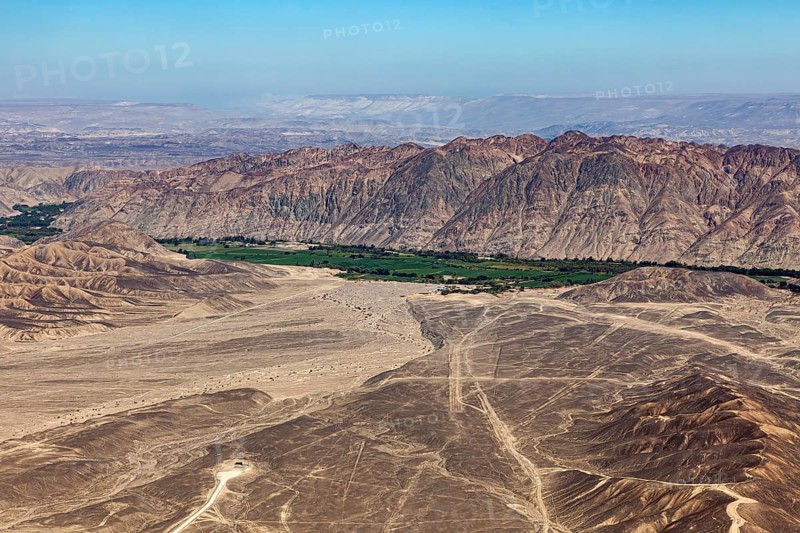 Dramatic desert plain with tracks and mountain panorama under clear sky, the desert landscape near Nasca in Peru