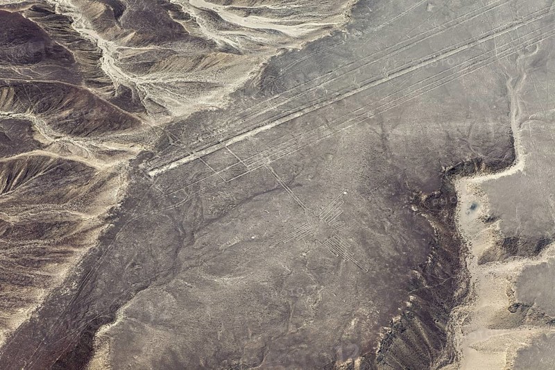 Geoglyphs in a vast sandy desert landscape with mountains, seen from the air, The geoglyphs and images in the desert near Nasca and Palpa in Peru