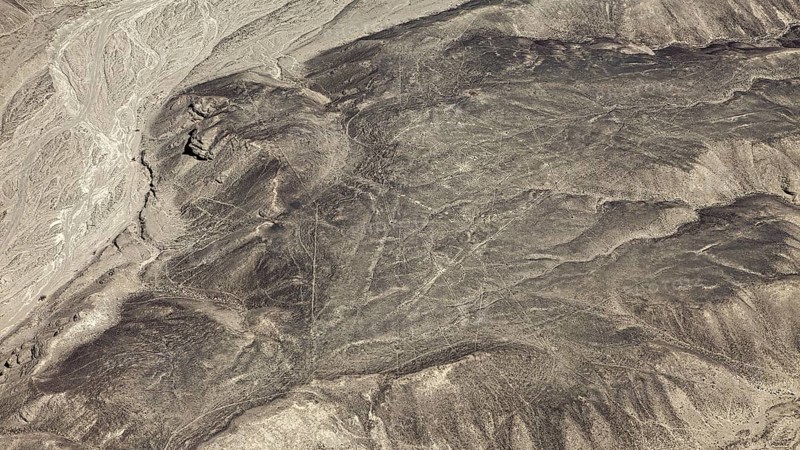 High-altitude view of a vast, dry landscape with linear structures, geoglyphs and drawings in the desert near Nasca and Palpa in Peru