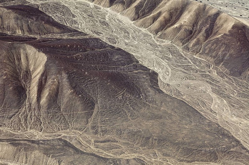 Aerial view of a desert with hills and ancient line formations, the geoglyphs and images in the desert near Nasca and Palpa in Peru