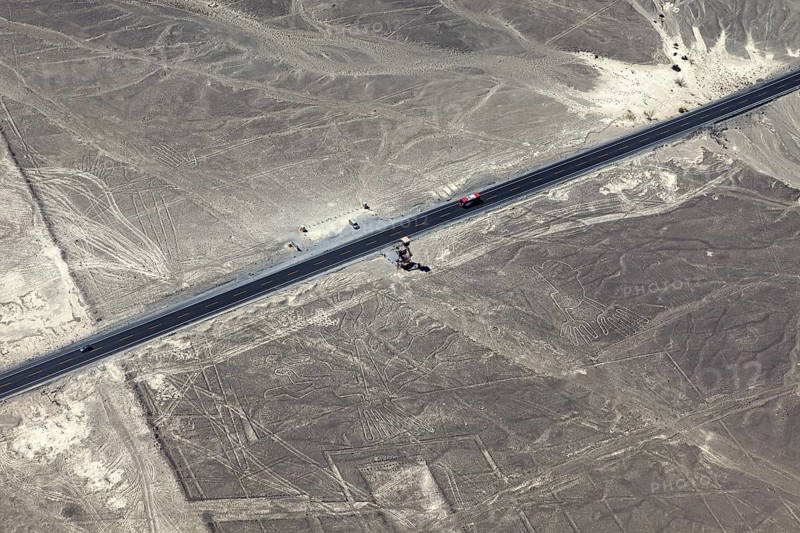 Aerial view of a dry environment with Nazca lines and a parallel road, The geoglyphs and images in the desert near Nasca and Palpa in Peru