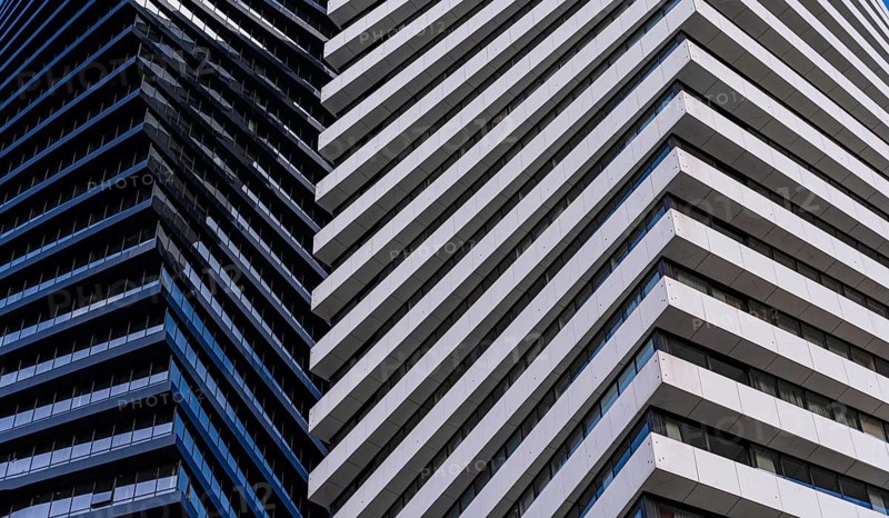 A close view of a modern skyscraper demonstrates contrasting architectural details, featuring alternating patterns of blue glass and white panels