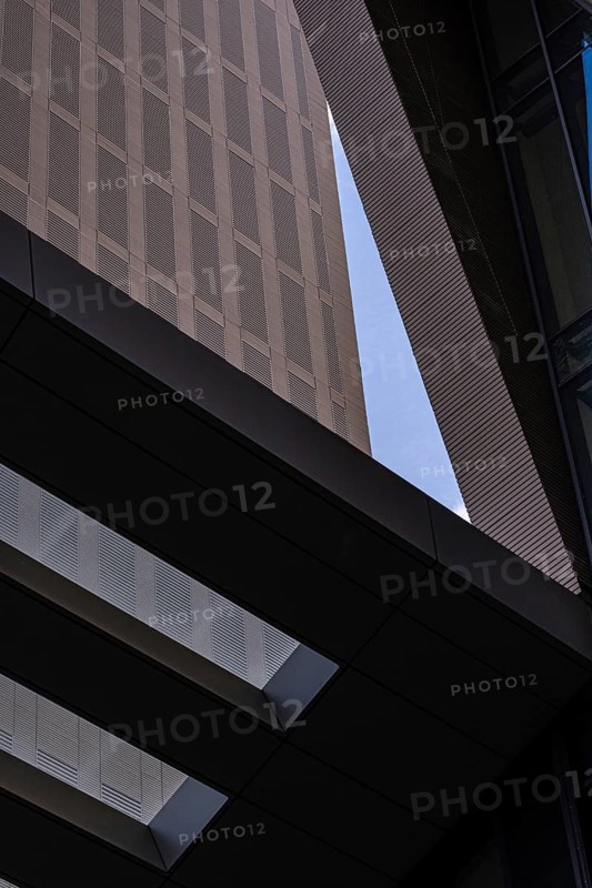 From below image captures the intricate textures and contrasting colors of modern architectural design, featuring a close view of a building's facade and its interplay with light and shadows