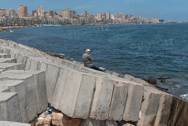 A man sits alone on the concrete breakwater, a barrier for potential flooding, the Egyptian Mediterranean city is at risk of rising sea levels, Egypt