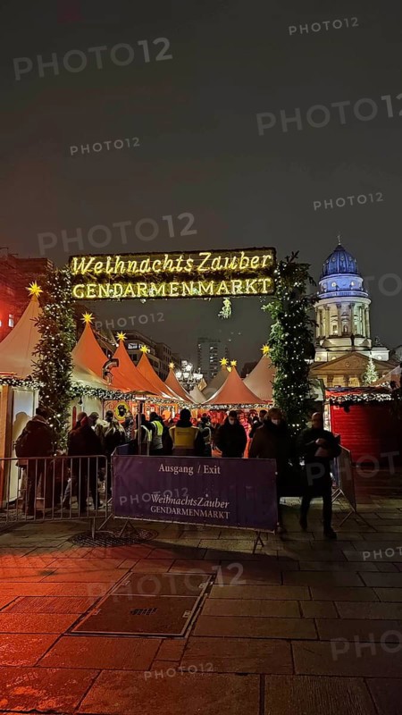 Christmas market at Gendarmenmarkt at night with bright lights and many visitors in a festive atmosphere, Berlin