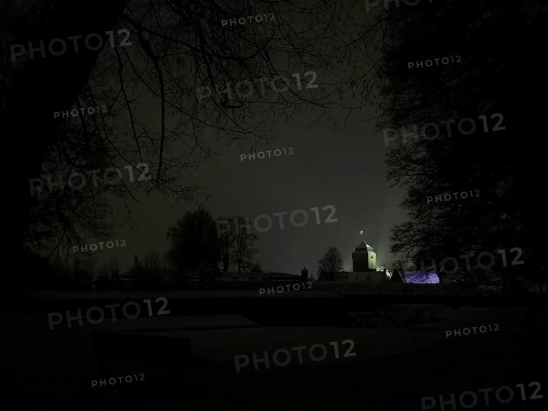 Night view of a dark landscape with a dimly lit, silhouetted Rosenberg Fortress, Kronach, Frankenwald nature park Park