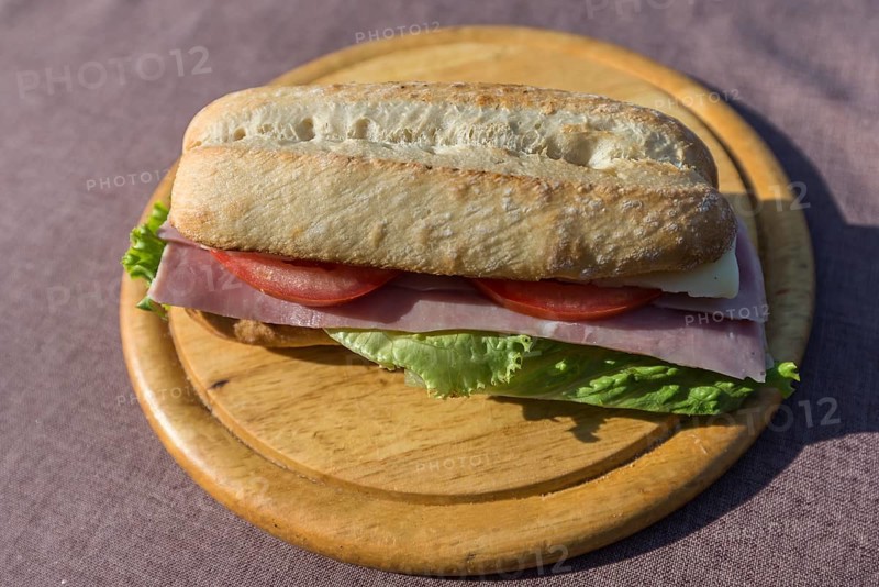 Ham and cheese baguette on a wooden plate, Italy