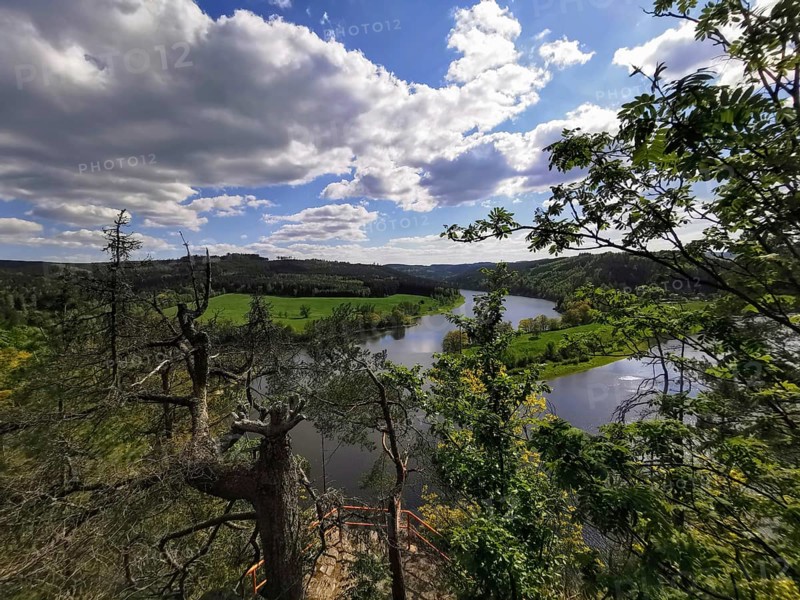 Extensive view of a river and forest from a viewpoint under a blue sky, hiking in the Thuringian Forest nature park Park