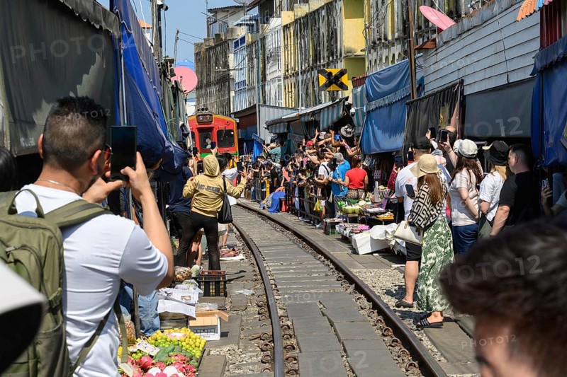 Mae Klong, Thailand. March 15th 2025. Tourists gather on the rail lines as the 14.30 train passes through the Mae Klong Railway market, in Samut Songkhram province of Thailand