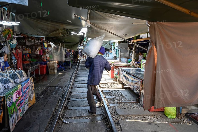 Mae Klong, Thailand. March 15th 2025. A market trader carries a bag of ice in the Maeklong Railway market, in Samut Songkhram province of Thailand