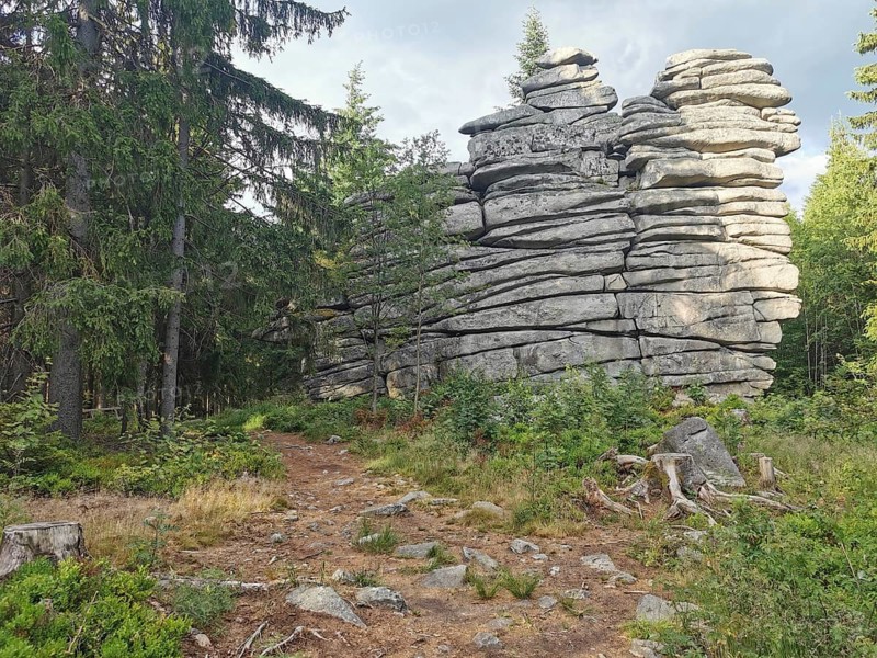 Large rock formations surrounded by trees and vegetation in a forest, Franconian mountain trail, hiking in the Fichtelgebirge nature park Park