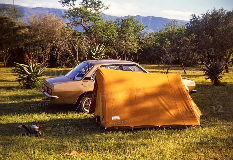 Car and small tent at campsite amongst tropical trees with camp cooking equipment, South Africa, Africa 1979