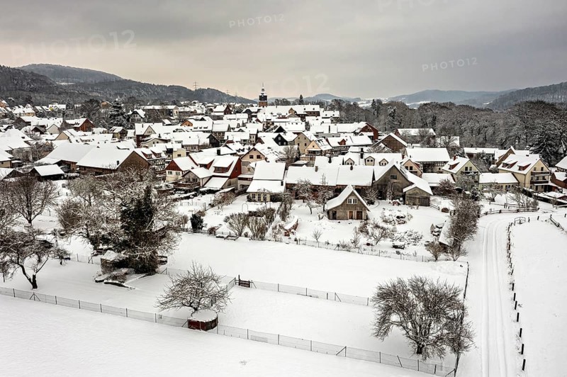 Snowy village with half-timbered houses and gardens under a grey sky, Herleshausen in northern Hesse