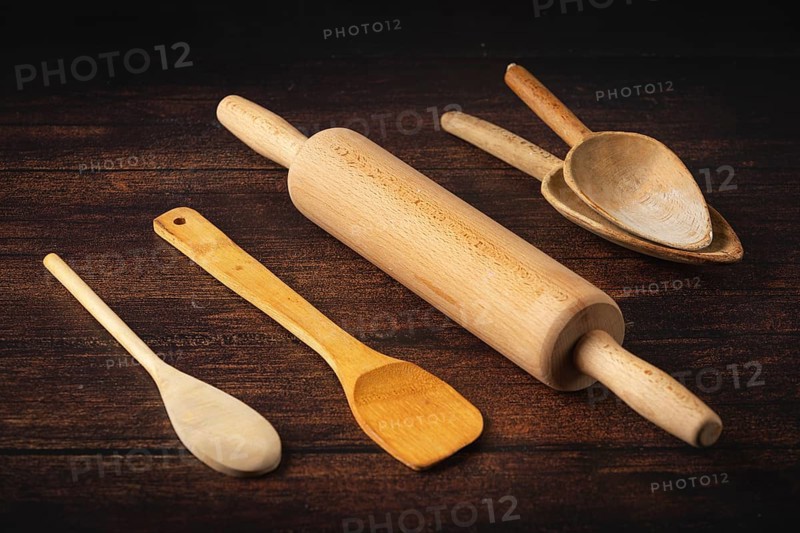 Rolling pin and wooden utensils on a dark wooden table in a rustic atmosphere