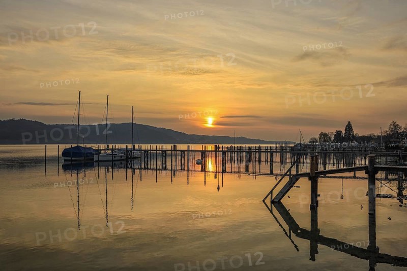 Atmospheric sunrise scene with calm water and sailboats on the jetty, Lake Constance, Überlinger See, Bodman-Ludwigshafen, Konstanz district, Baden-Württemberg, Germany