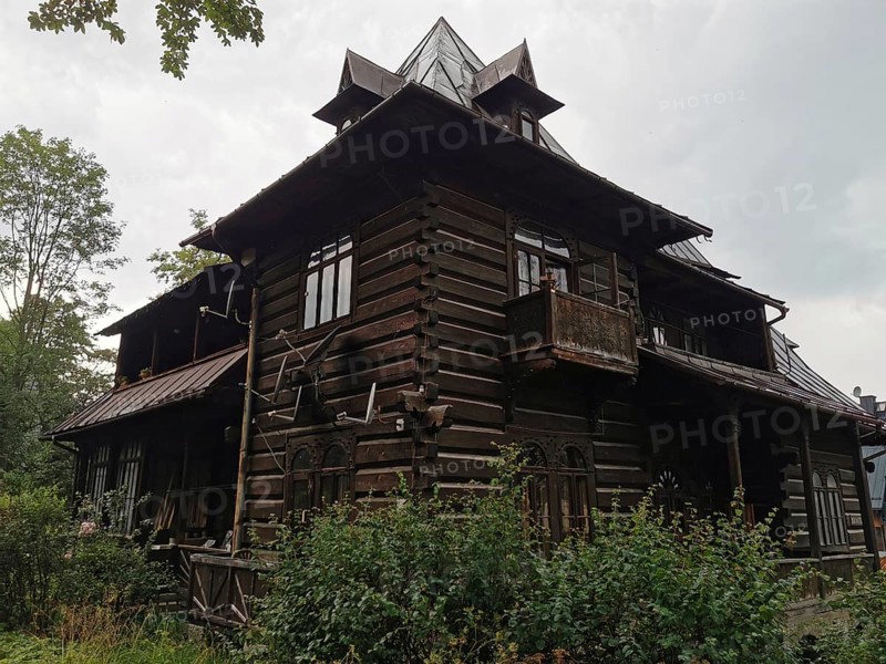 Old typical traditional Tatra wooden house with rustic architecture surrounded by trees under cloudy sky, Zakopane, hiking in the High Tatras National Park, Carpathian Mountains, Poland