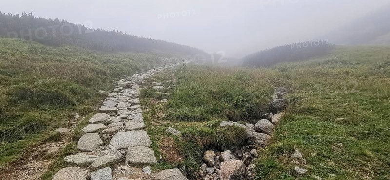 Rocky hiking trail through hilly, foggy landscape, Zakopane, hike to Kasprowy Wierch in the High Tatras National Park, Carpathian Mountains, Poland