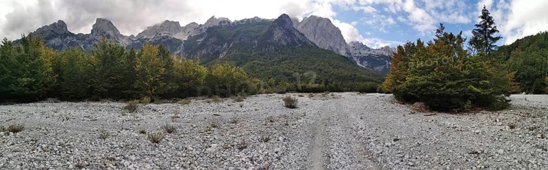 Panorama, wide riverbed in front of a wooded mountain landscape under blue sky and clouds, Peaks of the Balkans, hiking in the Albanian Alps National Park, Albania