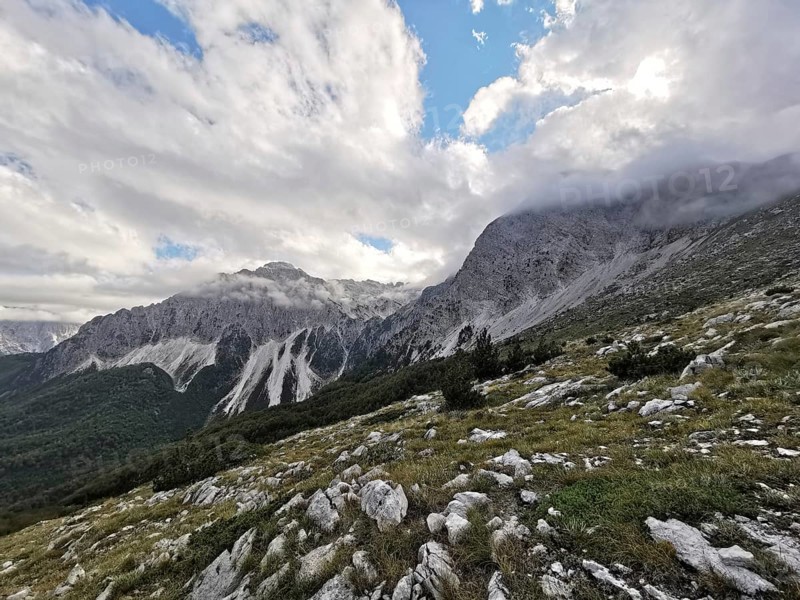 View of a mountainous landscape with dramatic clouds and rocks in the foreground, Peaks of the Balkans, hiking in the Albanian Alps National Park, Albania