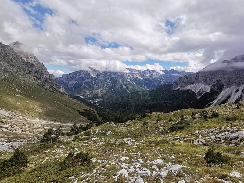 View of magnificent mountain landscape with a winding valley and clouds, Peaks of the Balkans, hiking in the Albanian Alps National Park, Albania