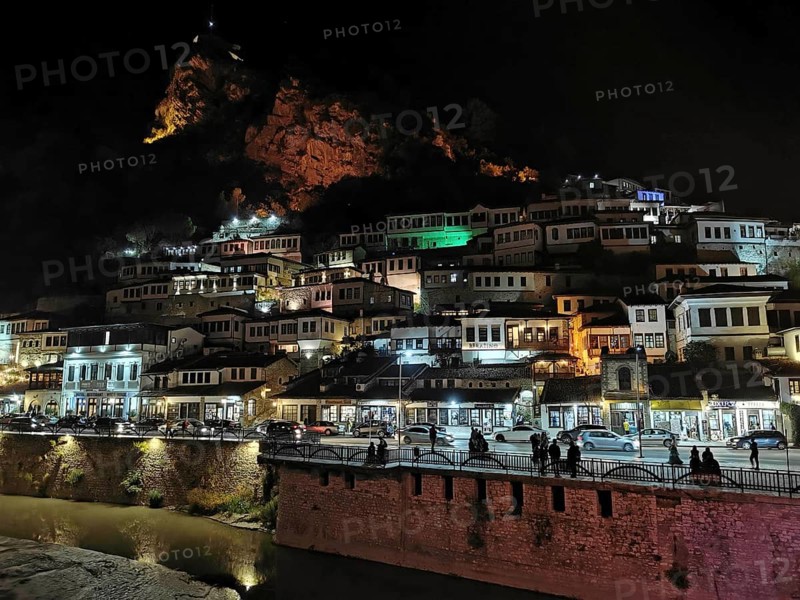 Night view of an illuminated city on the slope of a hill with river in the foreground, Berat, Albania