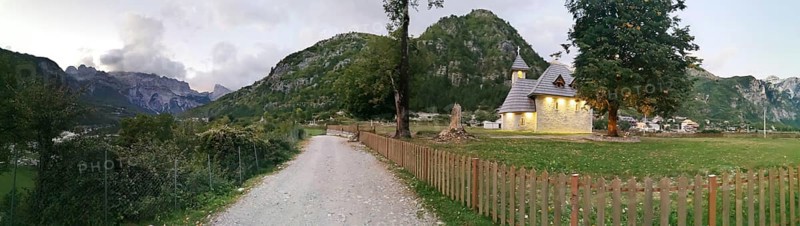 Picturesque church in Theth, a village with mountains in the background and a garden fence, Peaks of the Balkans, hiking in the Albanian Alps National Park, Albania