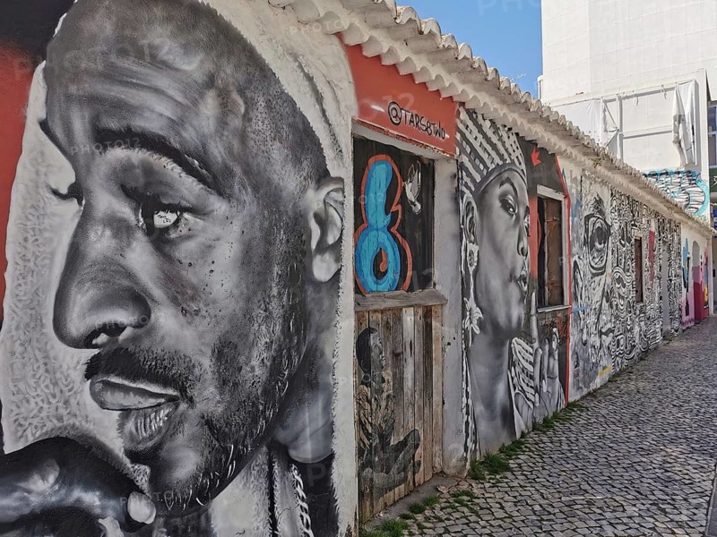 Wall with large-format graffiti in black and white of several expressive faces, Lagos, Algarve, Portugal