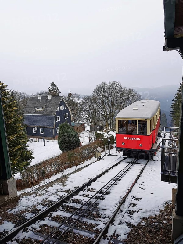 Red train goes through snow-covered mountain landscape, Oberweissbach cable car, Rennsteig, Thuringian Forest nature park Park