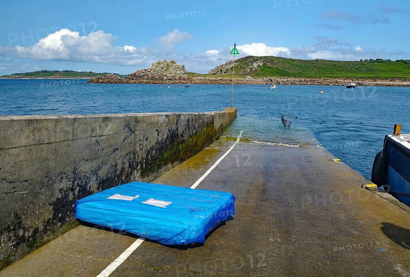 Small pier leading into the sea, colorful sky with clouds, boats and rocks in the background, St Agnes, Isles of Scilly, Cornwall, Great Britain