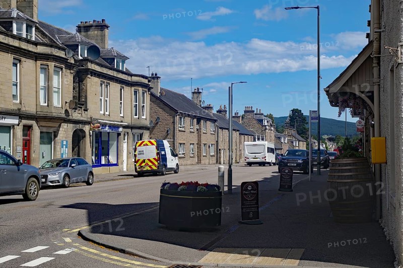Urban street scene with cars and buildings under blue sky, Dufftown, Aberdeenshire, Scotland, United Kingdom