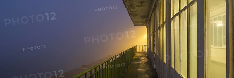 View along a long balcony of Steubenhöft at night in fog, Cuxhaven, Lower Saxony, Germany