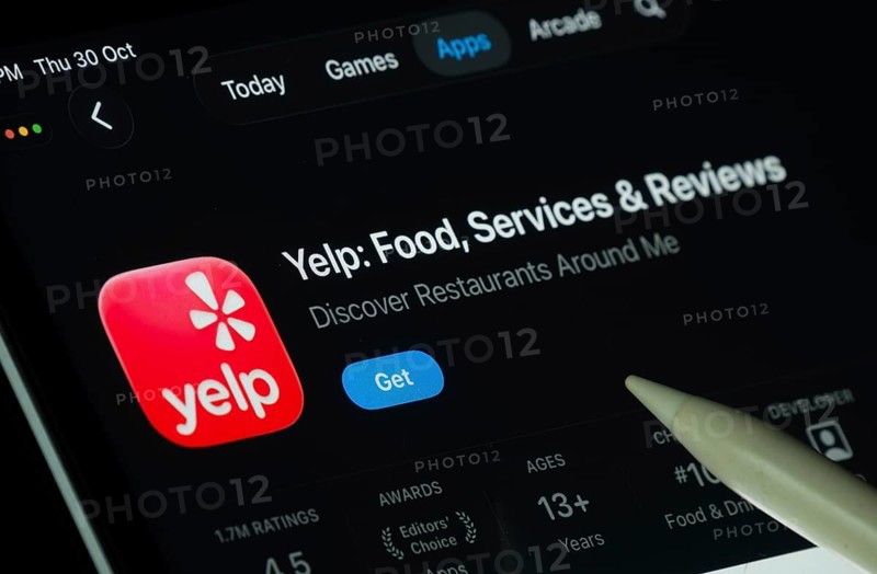 Dhaka, Bangladesh- 30 Oct 2025: Yelp app displayed on a iPad screen in dark mode with a digital pen pointing at it