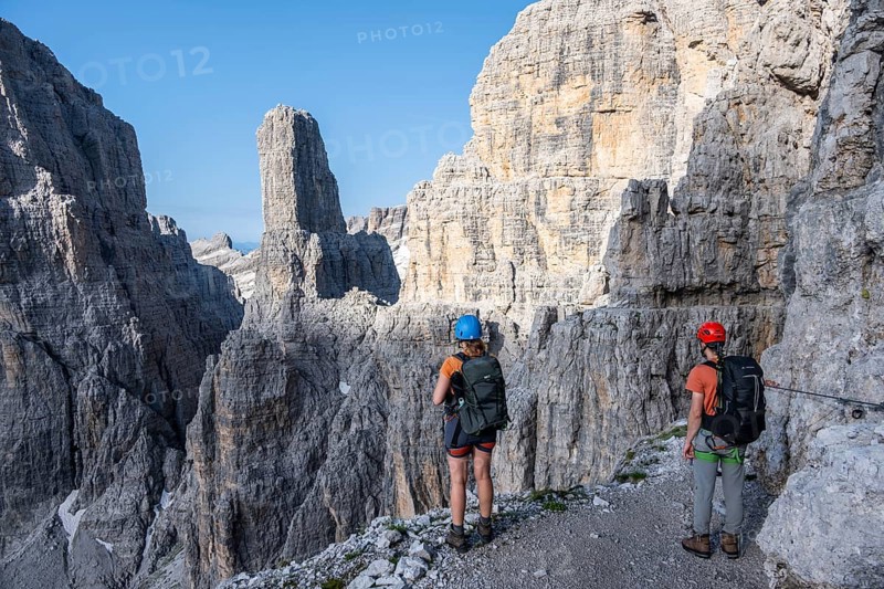Mountaineers look at Campanile Alto pinnacle, Bocchette Centrale band trail, via ferrata in the Brenta Mountains, Parco Naturale Brenta-Adamello, Trentino, Italy