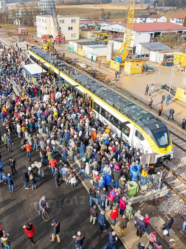 Many people gather at an event near a construction site by train at a train station, opening of the Hermann Hesse Railway, Calw, Germany