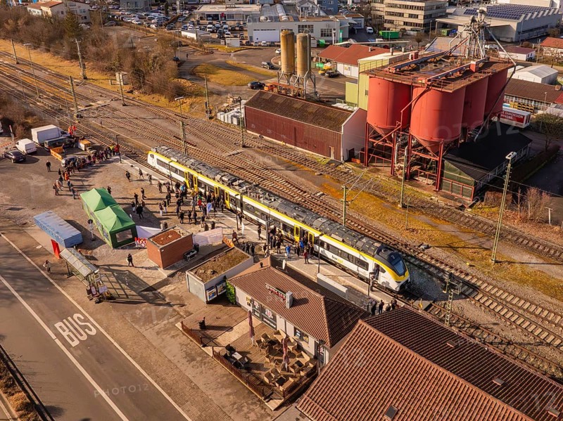 Industrial site with a passing train, surrounded by people and various buildings, opening of the Hermann Hesse Railway, Calw, Germany