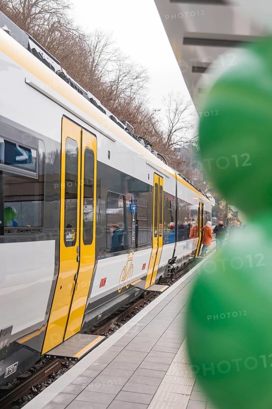 Yellow and white train on a platform with colorful balloons in the foreground, opening of the Hermann Hesse Railway, Calw, Germany
