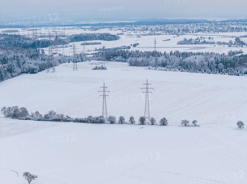 Wide snow-covered fields with power lines and small villages on the horizon in cold weather, substation, Jettingen, Germany