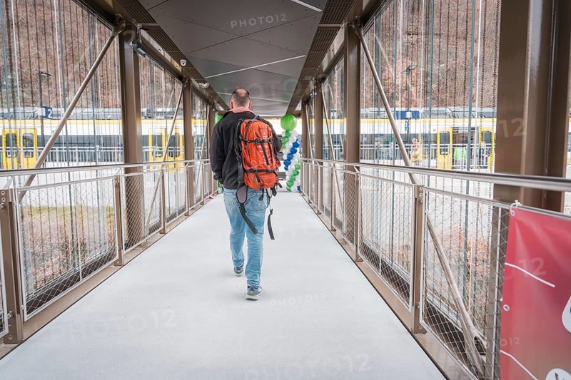 Man with backpack walking across bridge, yellow train in background, battery electric train Siemens Micro Plus B, Hermann, Hesse, Bahn, Weil der Stadt, Böblingen district, Germany