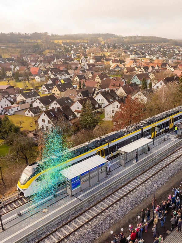 Train stops at a train station in a small town with many spectators and houses in the background, opening of the Hermann Hesse Railway, Calw, Germany
